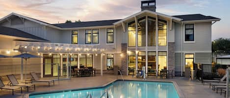 A two-story house with a swimming pool, outdoor seating, and a covered patio area.