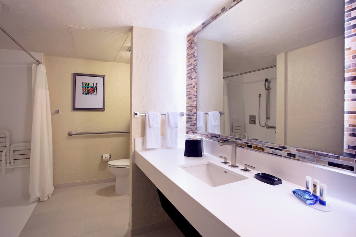 A modern bathroom with a white sink, a large mirror, and a shower area.
