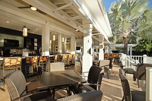 An outdoor bar area with seating and a television screen. - Compass Hotel by Margaritaville Key West (Key West)