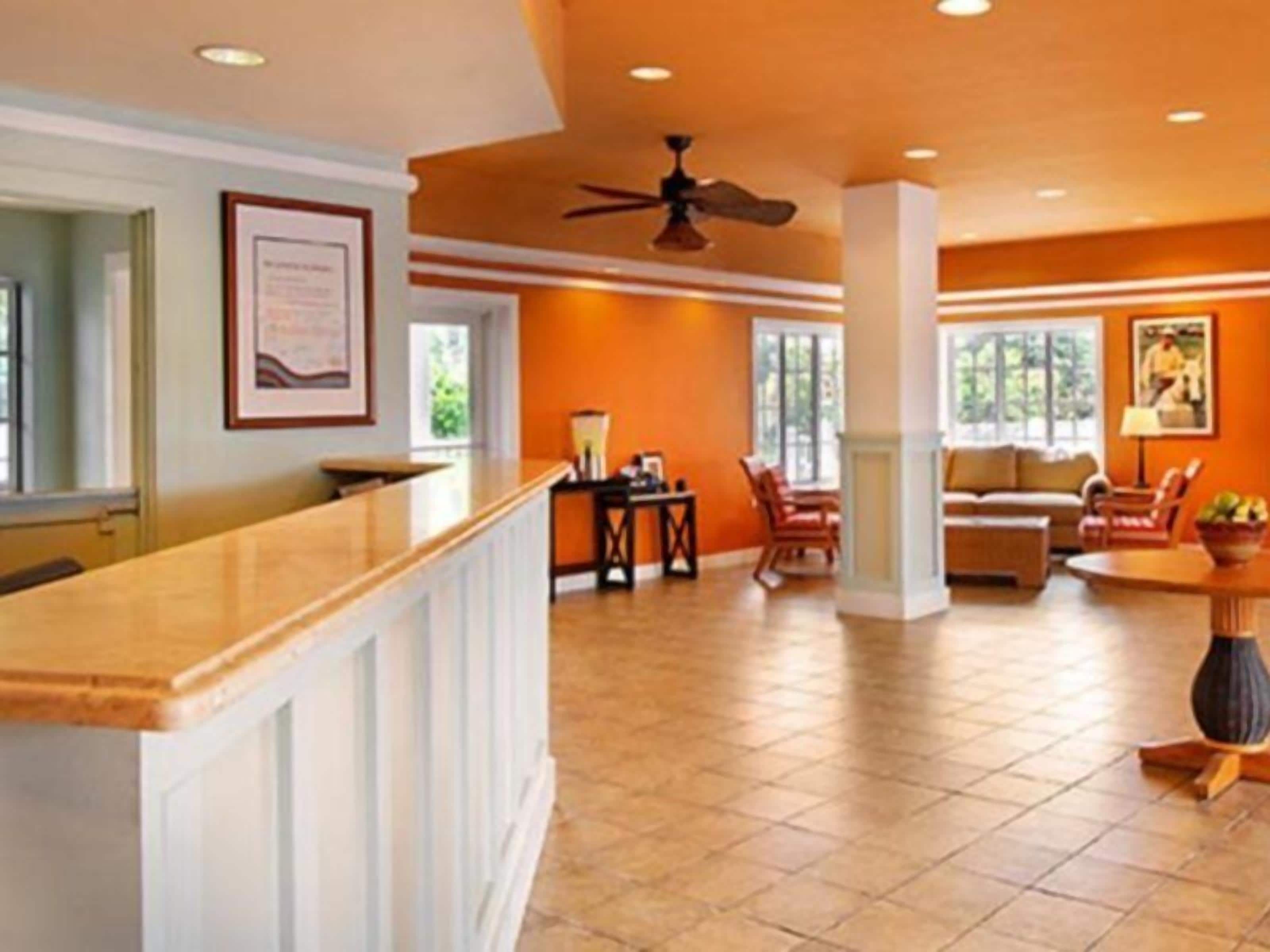 A hotel lobby with a reception desk, seating area, and large windows.