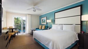 A hotel room with a large bed, a desk, a chair, a balcony with a view, and a ceiling fan. - Fairfield Inn and Suites by Marriott Key West (Key West)