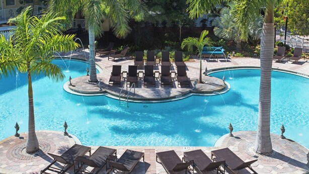 A pool area with lounge chairs, palm trees, and a fountain. - Fairfield Inn and Suites by Marriott Key West (Key West)