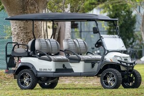 A golf cart with a black roof, grey seats, and black wheels.