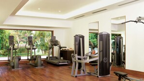 Uma academia moderna com equipamentos de cardio, aparelhos de musculação e um espelho grande.