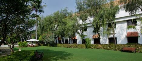 A courtyard with a lawn, benches, and a white building with red-tiled roofs.