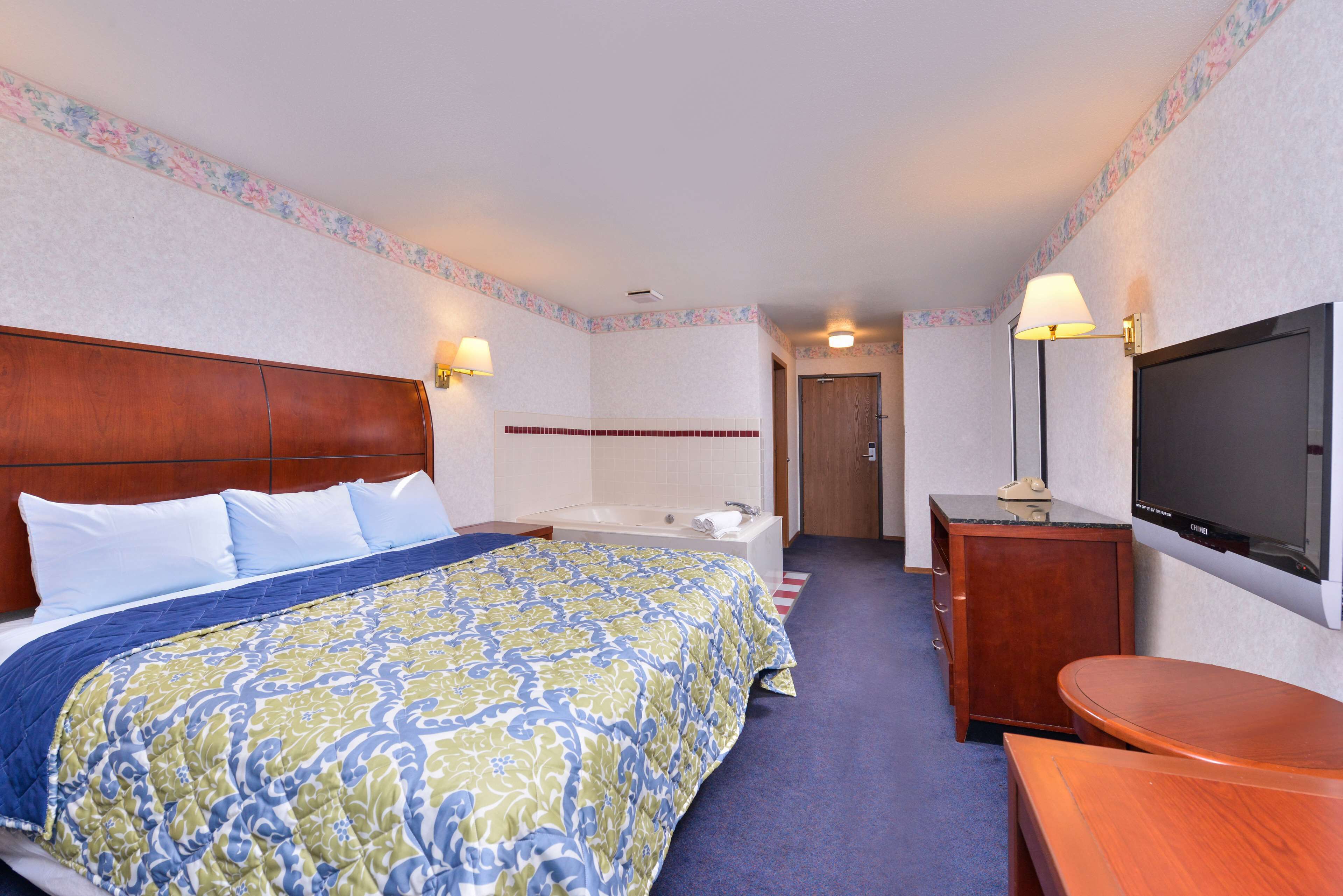 Une chambre d’hôtel avec un grand lit, une salle de bain, un bureau et une télévision.