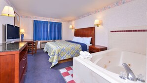 Ein Hotelzimmer mit Bett, Schreibtisch mit Fernseher, Badezimmer mit Badewanne und Fenster mit blauen Vorhängen.