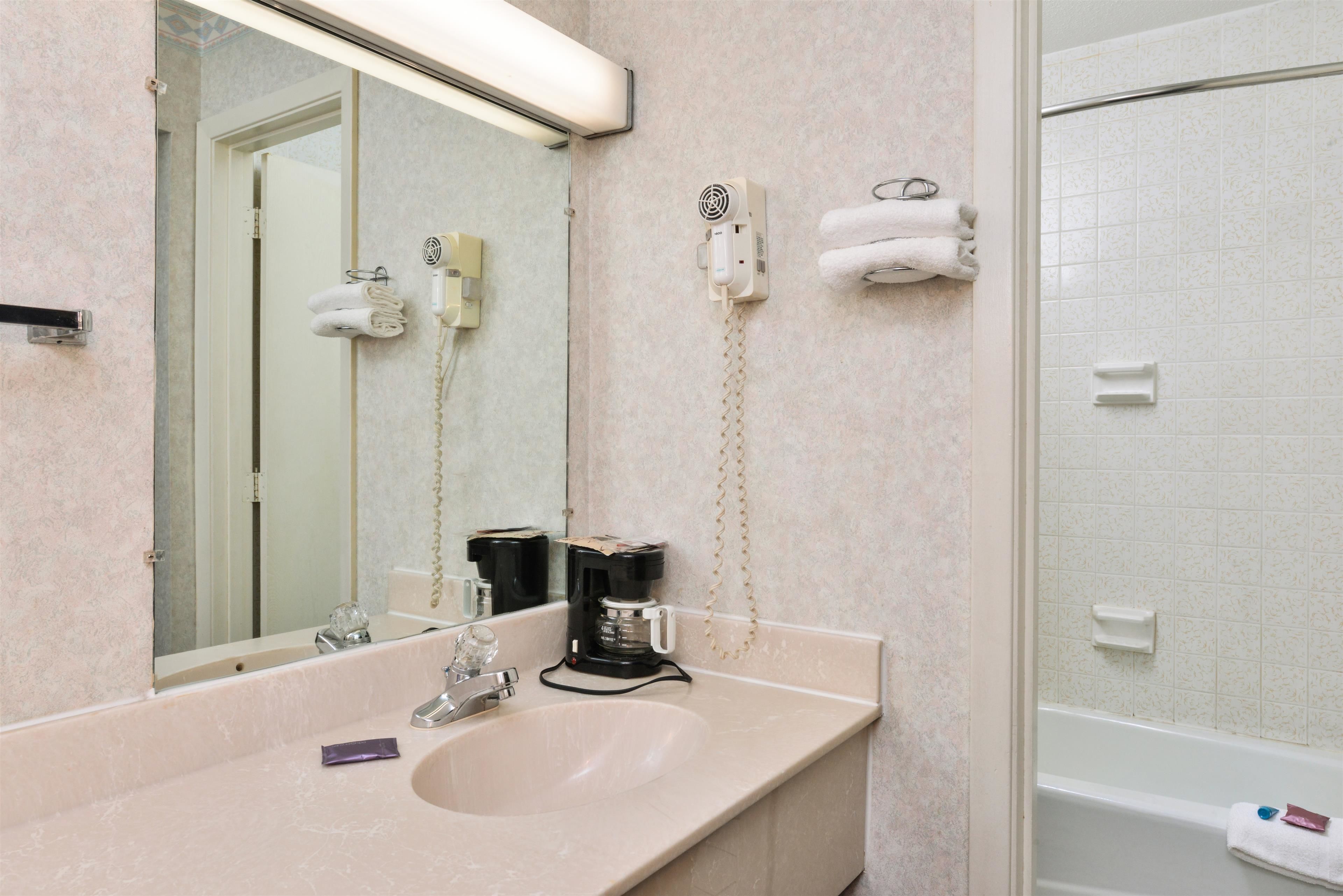 Une salle de bain équipée d’un lavabo, d’un miroir, d’un porte-serviettes et d’un espace douche.