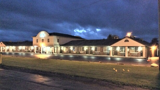 Ein Motel mit einem zentralen Hauptgebäude und mehreren angebauten Einheiten, alle mit Außenbeleuchtung.