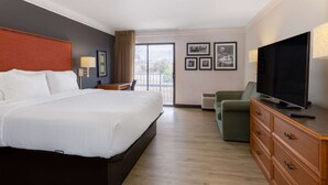 Une chambre d’hôtel avec un grand lit, une télévision, une commode et un balcon avec vue.