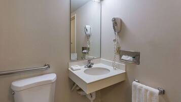 A bathroom with a toilet, sink, and a hairdryer mounted on the wall.