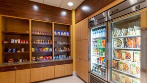 Une petite cuisine équipée de meubles en bois, d’un plan de travail et d’un réfrigérateur rempli de boissons et d’aliments.