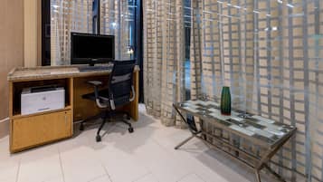 Un ufficio moderno con un computer da scrivania, una sedia d'ufficio e un tavolo in vetro con un vaso decorativo.