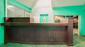 A reception desk with a dark wood finish, a ceiling fan, and a green accent wall. - Lake Place Inn (Lake Havasu City)