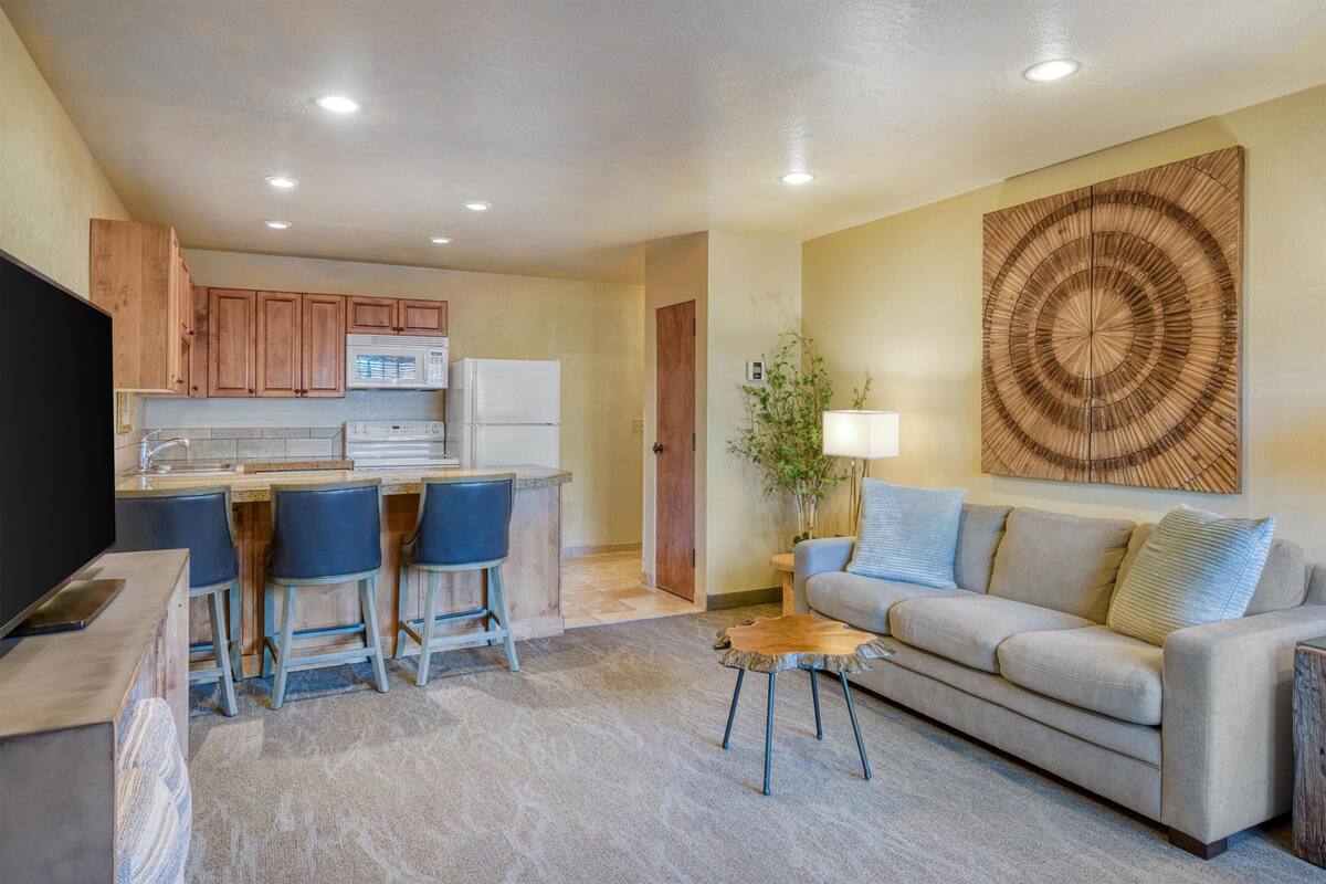 A modern living space with a kitchen, a sofa, a coffee table, and a TV.