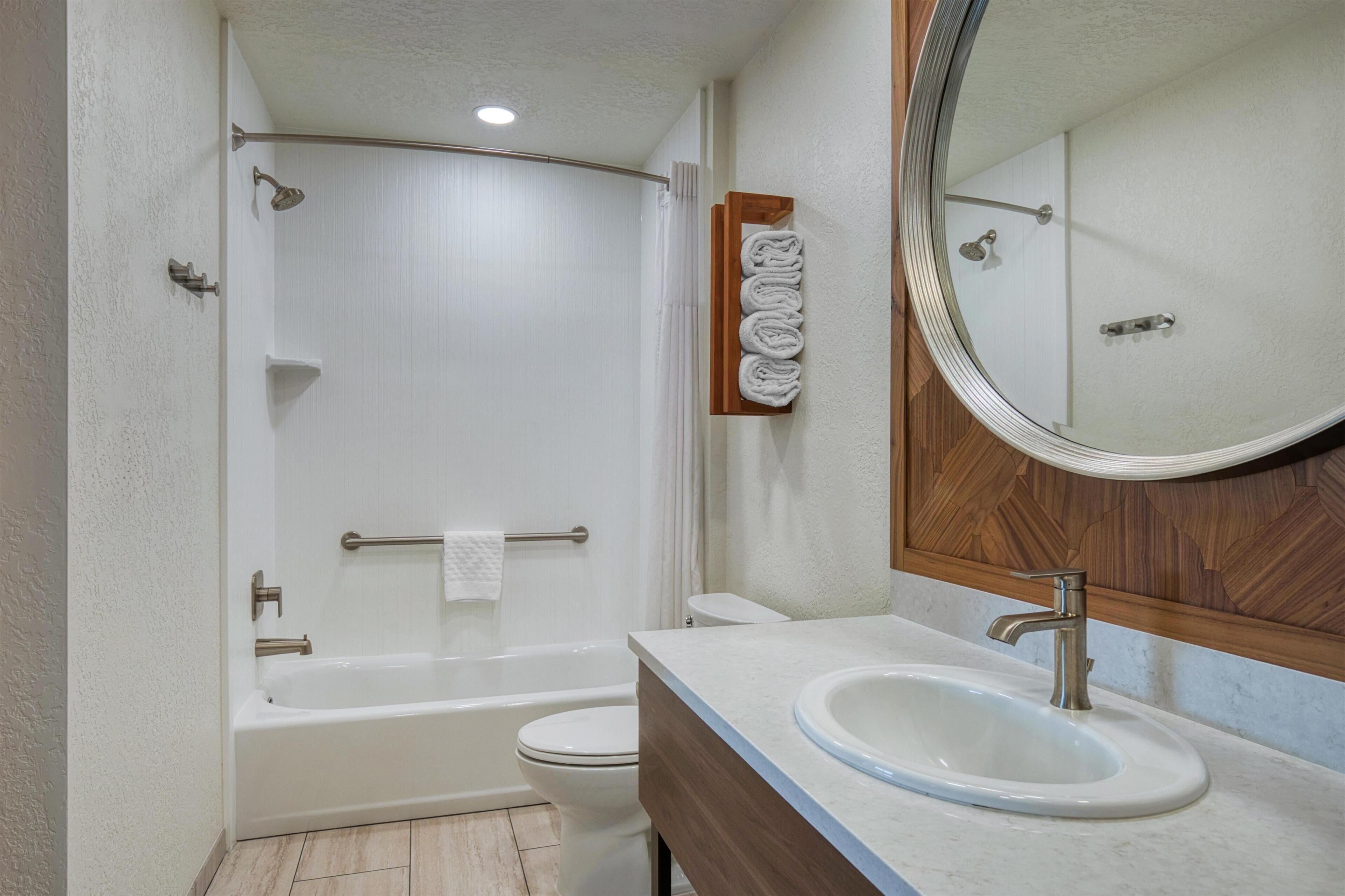 A bathroom with a bathtub, toilet, sink, and a mirror.