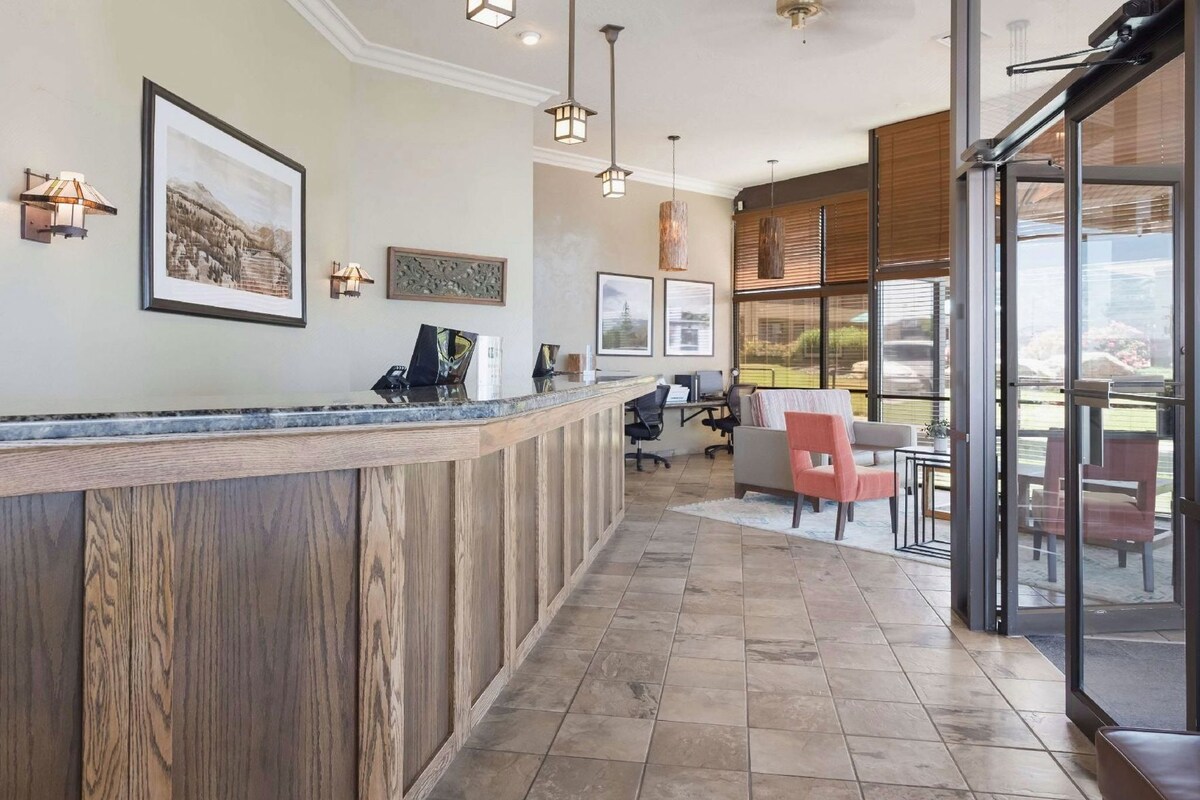 A reception area with a wooden counter, framed artwork, and a seating area with chairs and a table.