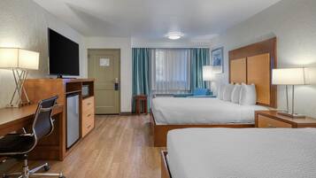Une chambre d’hôtel équipée d’un lit, d’un bureau, d’une chaise, d’une télévision et d’une fenêtre avec des rideaux.