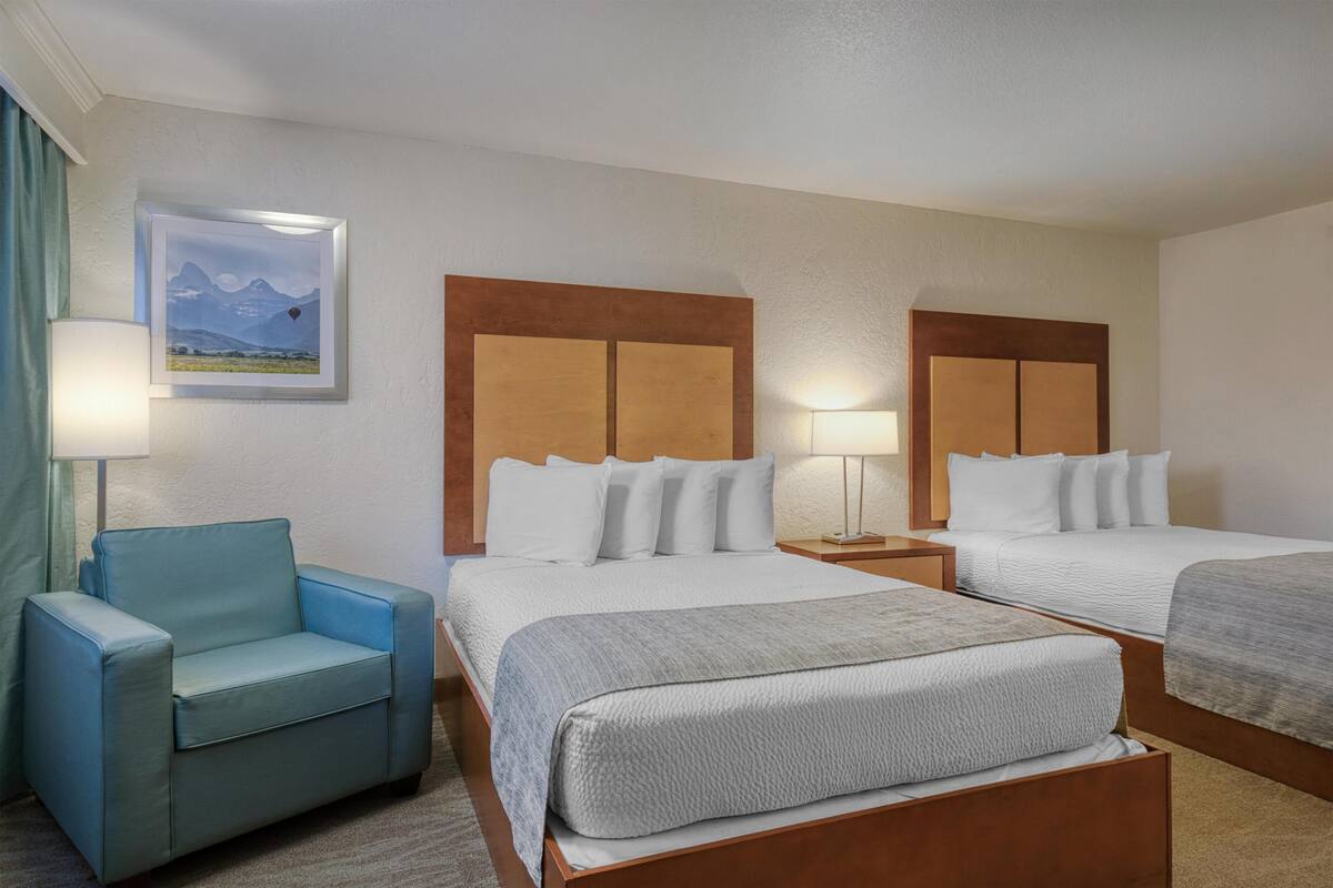 A hotel room with two beds, a sofa, and a painting on the wall.
