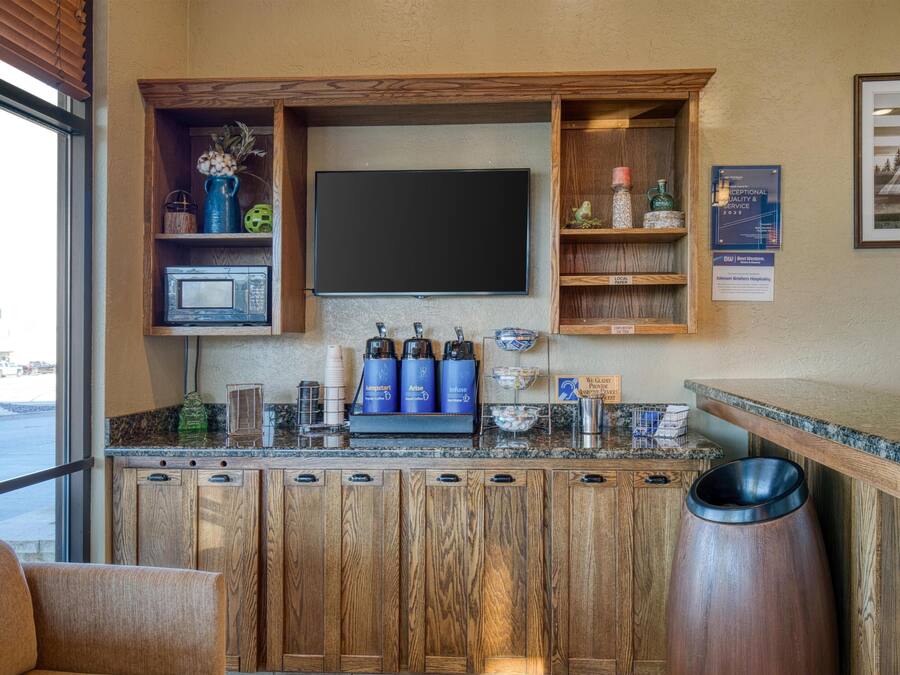 A bar area with wooden cabinets, a flat-screen TV, and coffee makers.