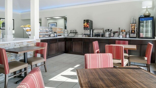 A modern restaurant with a central island, red upholstered chairs, and a variety of food and beverage dispensers.