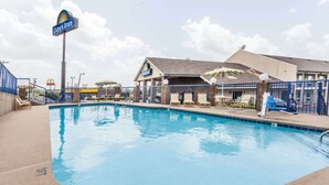 A Days Inn pool area with a clear sky, a covered seating area, and a fenced pool. - Days Inn by Wyndham Nashville North/Opryland Area (Nashville)