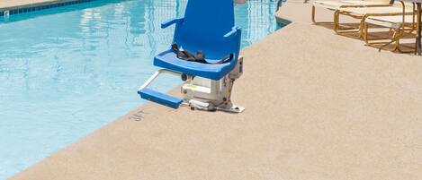 Una piscina con sillas de descanso y un puesto de socorrista.
