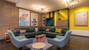Una sala de estar moderna con un sofá modular, dos sillones, una mesa de centro y una estantería.