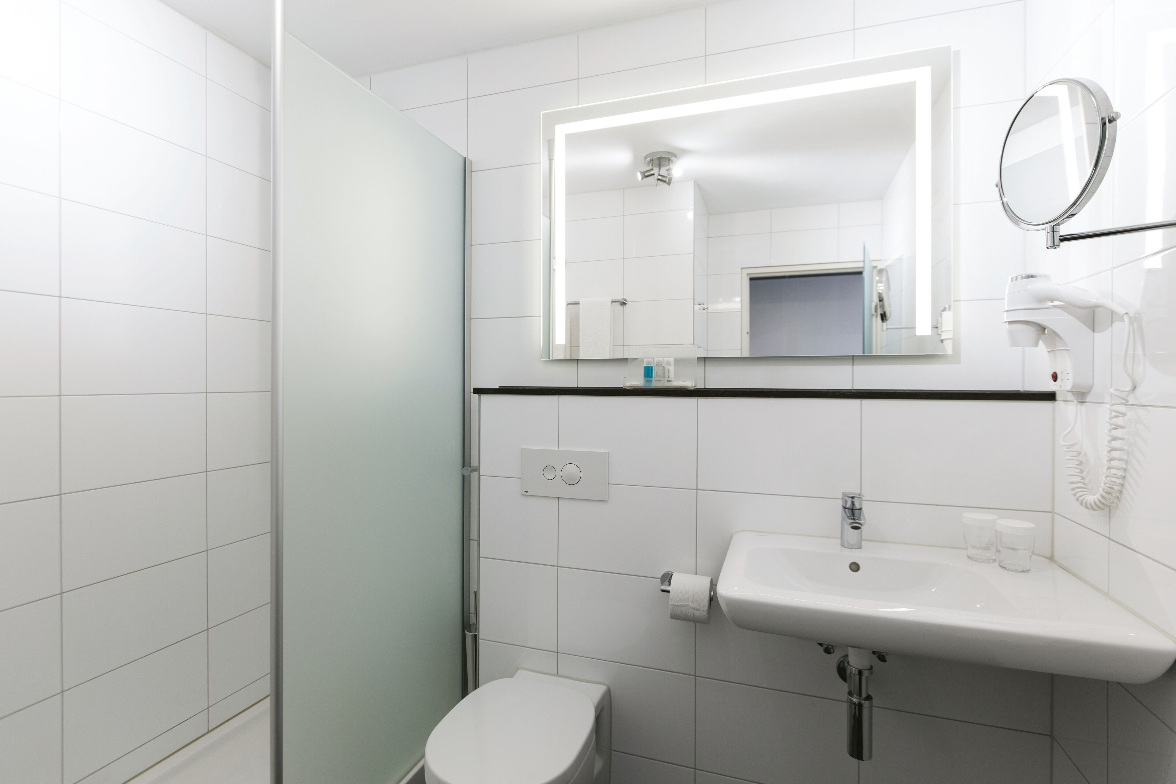 A modern bathroom with a toilet, sink, and mirror.
