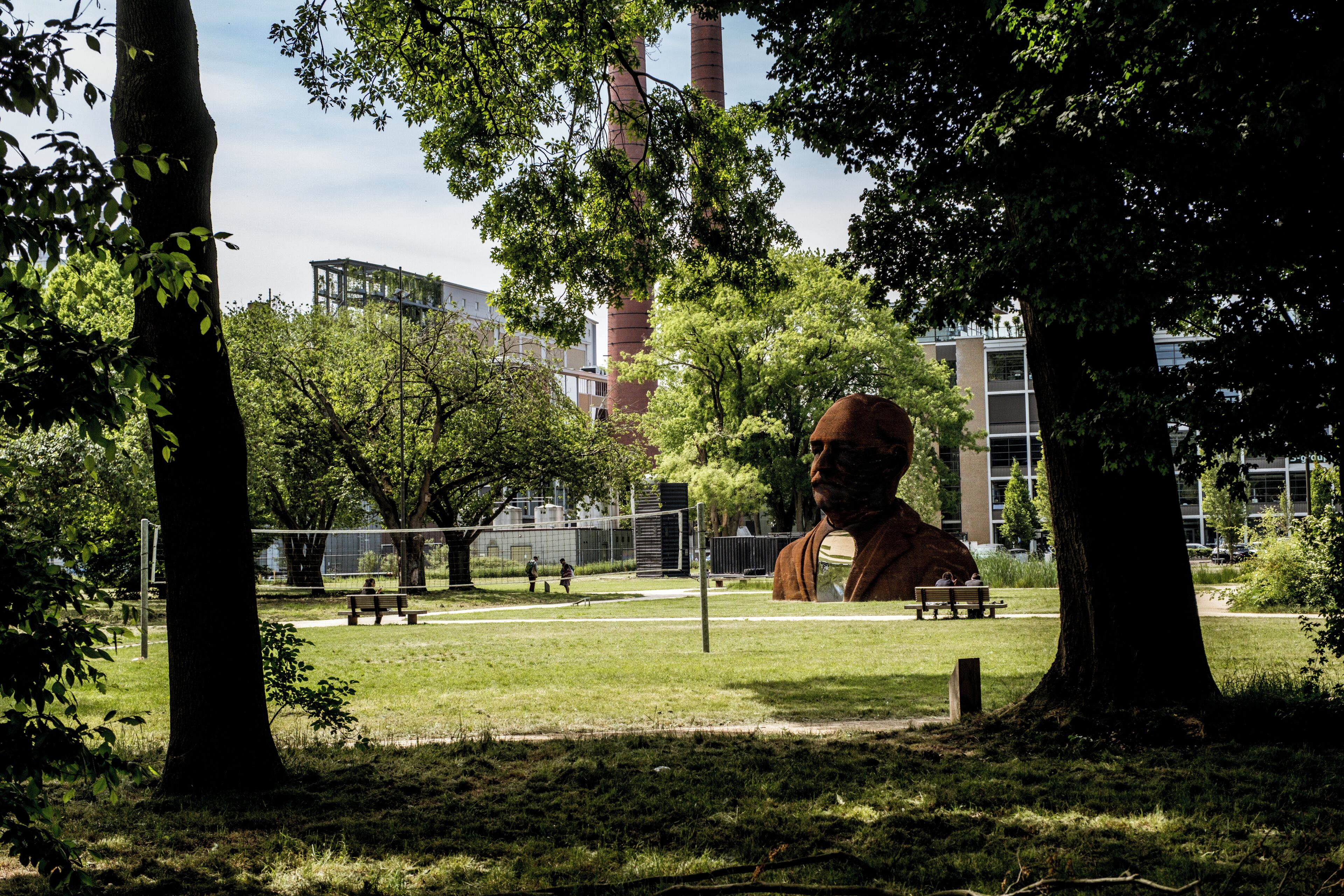 A park with trees, a statue, and a building in the background.