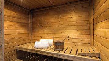 A wooden sauna with benches and a wooden bucket with a ladle.