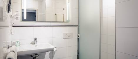 Uma casa de banho moderna com uma pia branca, espelho e sanita.