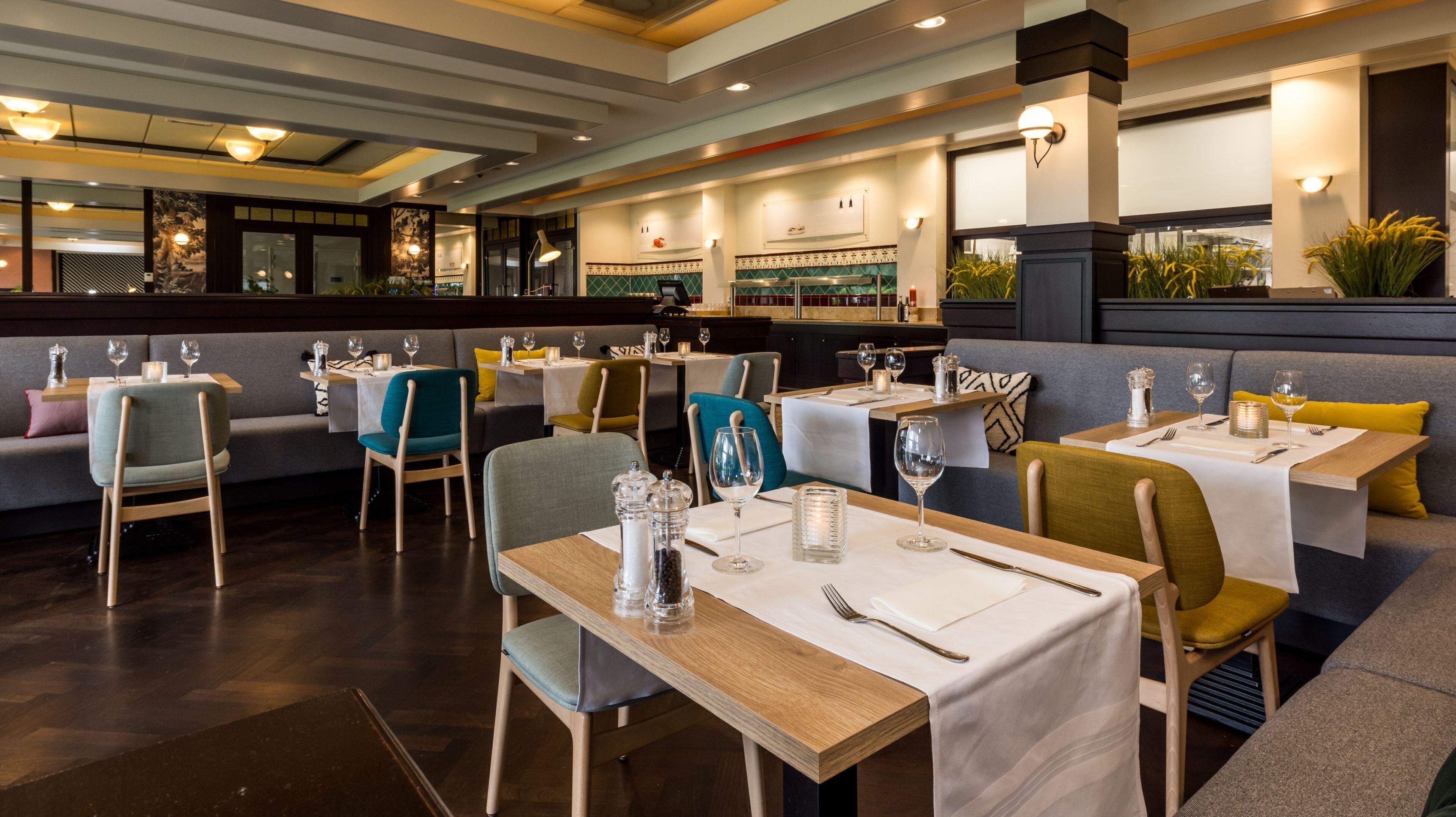 Un interior de restaurante con cabinas y mesas, piso de madera e iluminación decorativa.