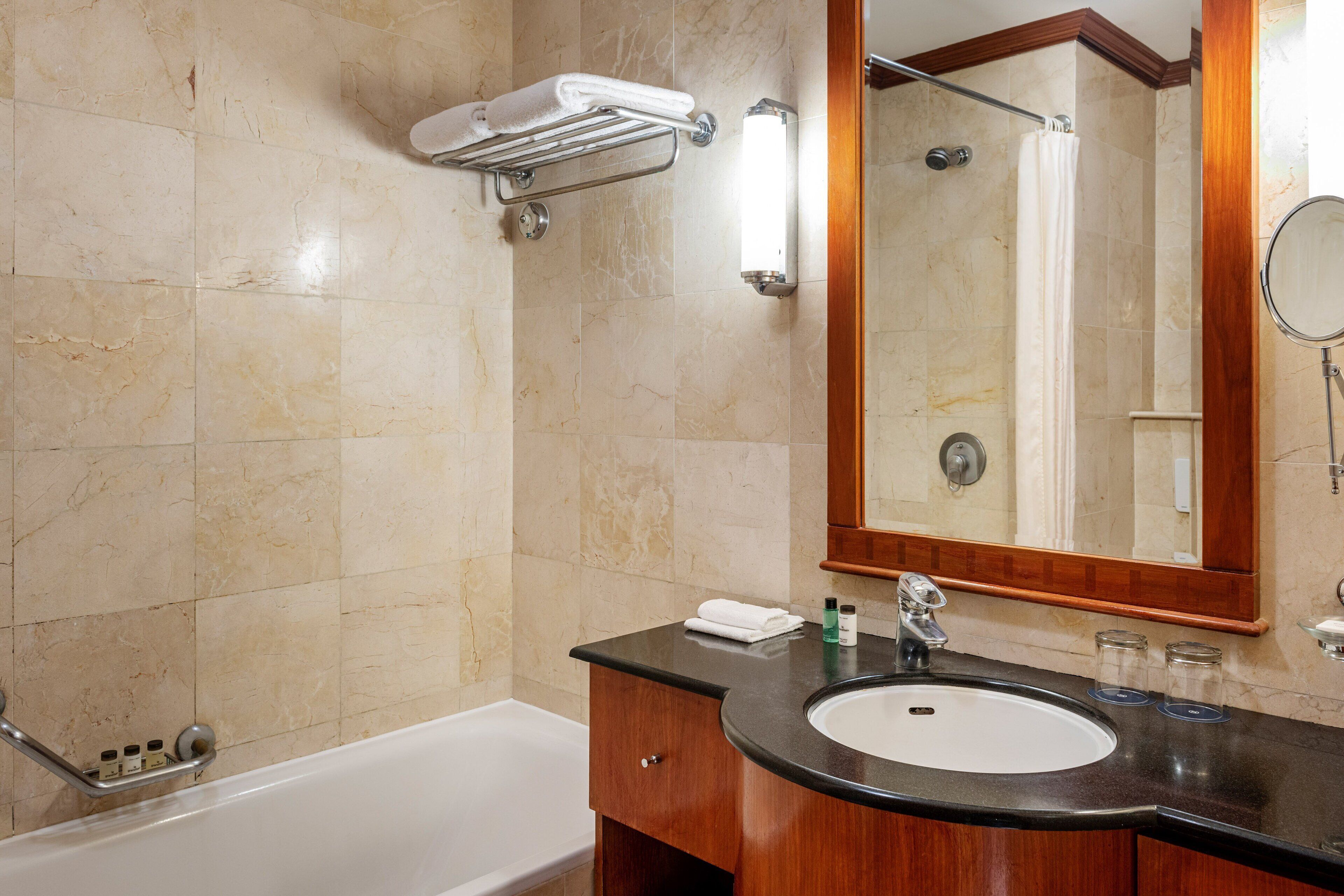 A bathroom with a bathtub, a sink with a mirror, and a towel rack.