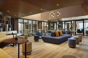 Eine großzügige Lobby mit modernem Design, ausgestattet mit einer geräumigen Sitzecke, Sofas und Sesseln, einem Holzboden und großen Fenstern mit schöner Aussicht.