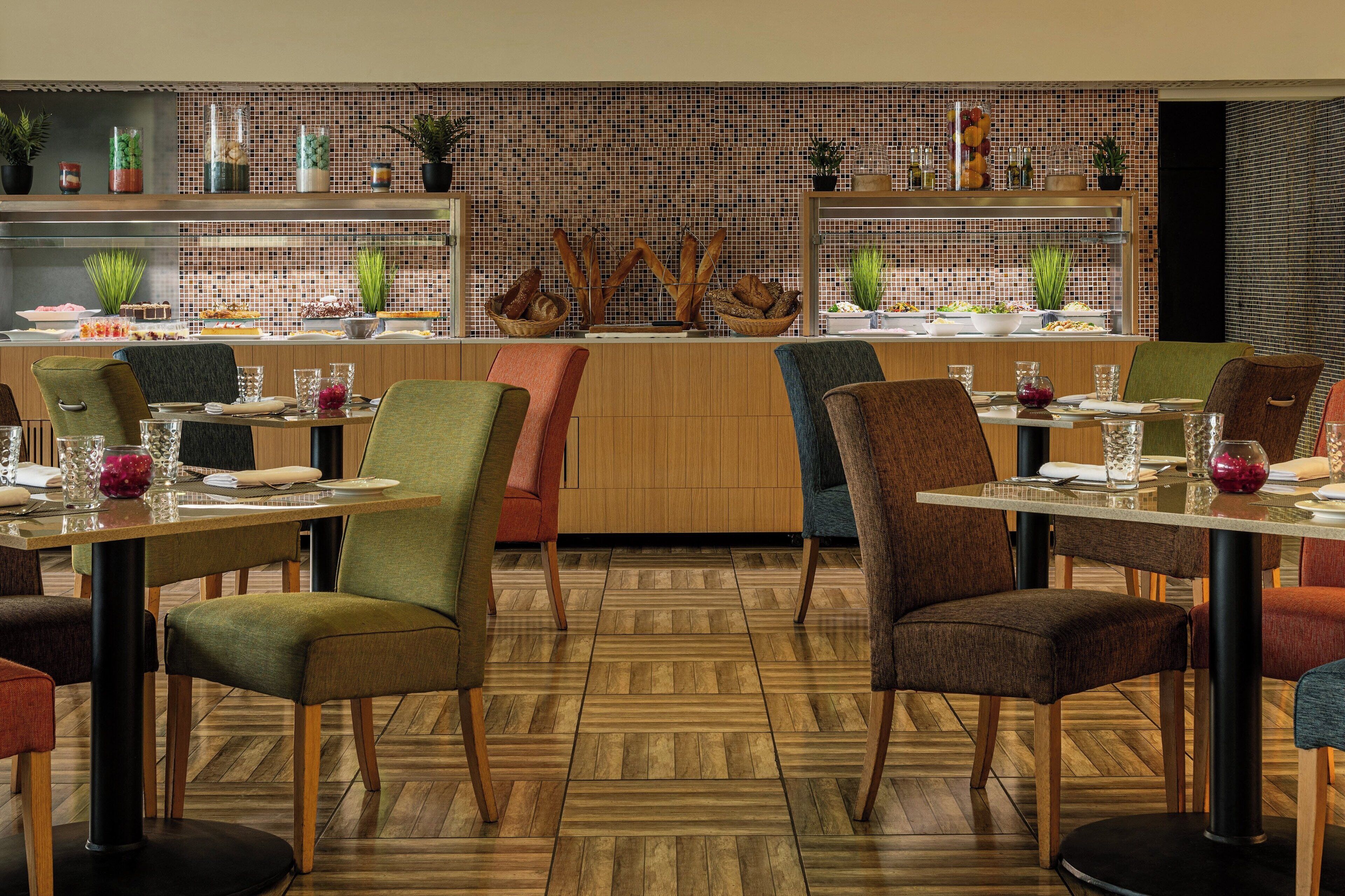 Un restaurante con suelo de madera, varias mesas y sillas.