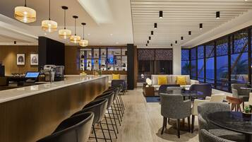 A modern hotel lobby with a bar area, seating arrangements, and large windows offering views.