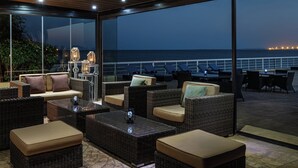 Un espace extérieur aménagé avec des meubles en osier et offrant une vue sur la mer la nuit.