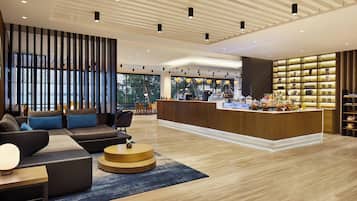 A modern lobby with a reception desk, seating area, and large windows.