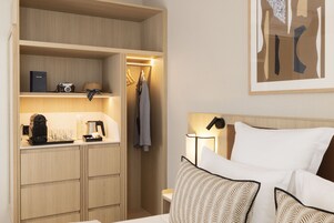 A hotel room with a bed, bedside table, and a wardrobe.