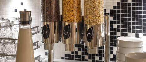 A coffee machine with multiple dispensers, a milk frother, and stacked white cups on a counter with a tiled backsplash.