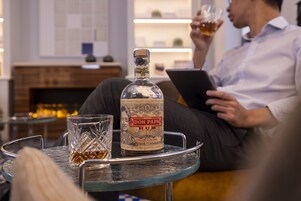 Una botella de ron Don Papa sobre una mesa de vidrio, con un vaso a un lado.