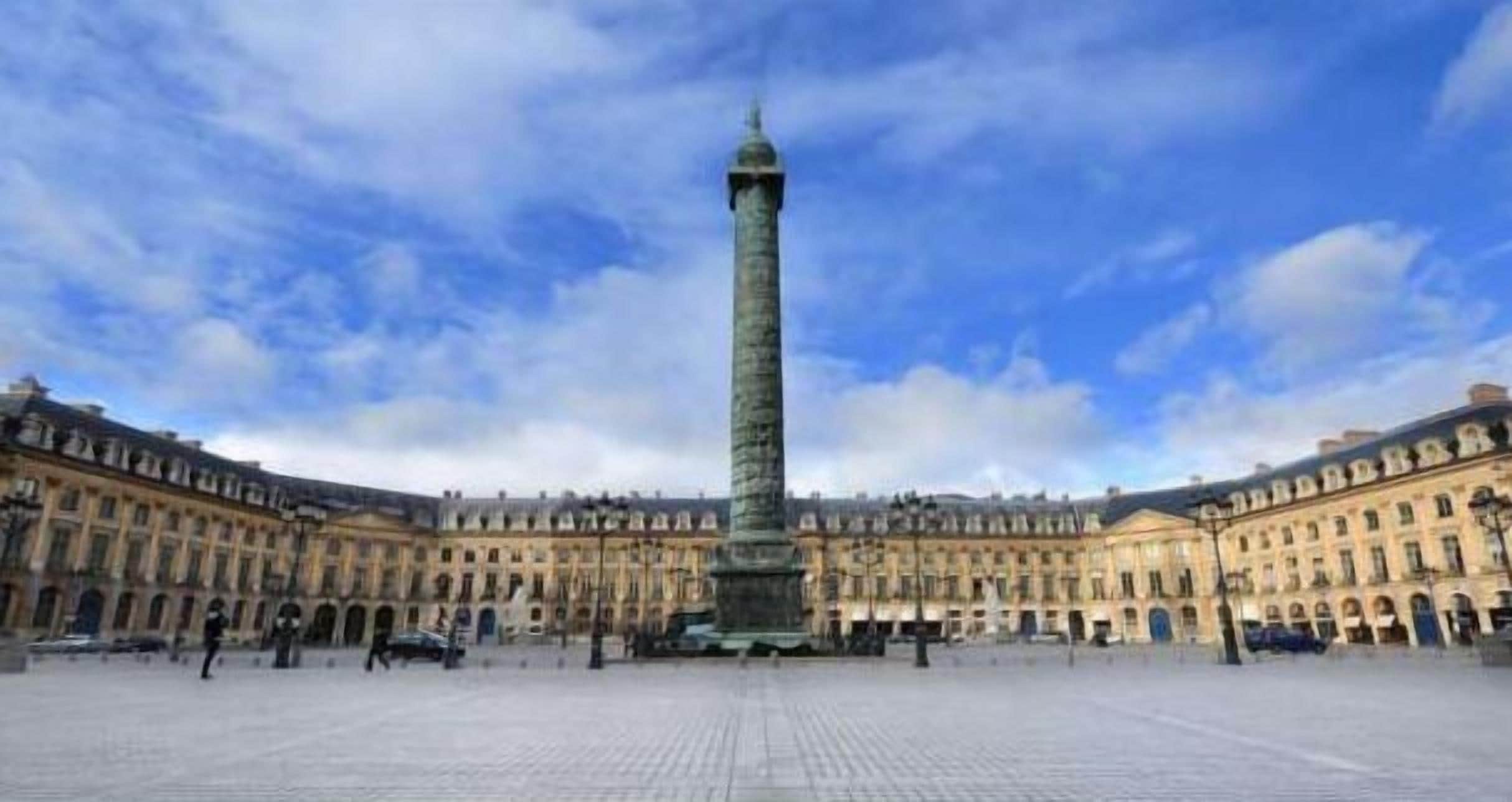 Una amplia plaza abierta con un obelisco alto en el centro, rodeada de edificios de estilo clásico y fachadas simétricas.