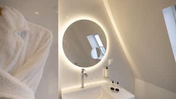 Un baño moderno con espejo redondo, lavabo blanco y un perchero para toallas.
