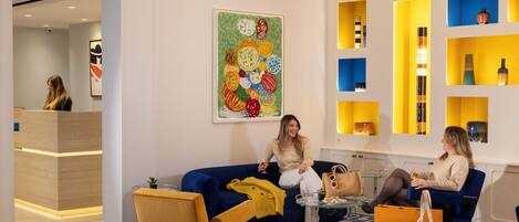 A modern lobby with a blue and yellow color scheme, featuring a reception desk, a blue sofa, and a patterned floor.