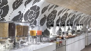 Un moderno bufé con recipientes de vidrio transparente llenos de diversos alimentos, techo con un diseño decorativo y un ambiente limpio y contemporáneo.