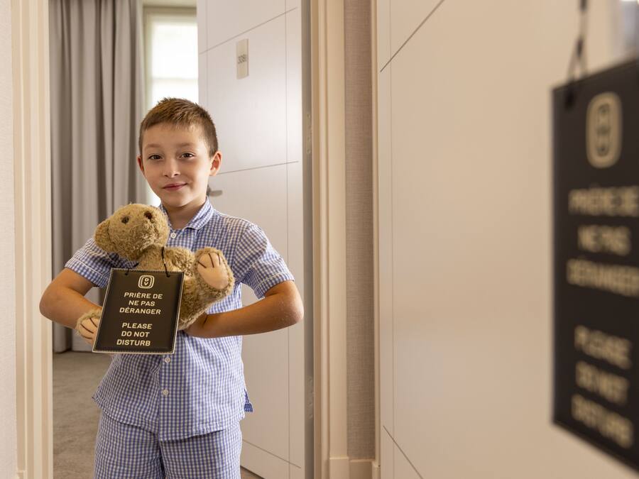 Une personne tenant un ours en peluche et une pancarte sur laquelle on peut lire : « Veuillez ne pas déranger. »