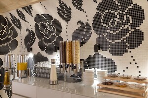 A modern kitchen with a mosaic backsplash, stainless steel appliances, and a buffet setup.