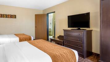 A hotel room with two beds, a television, a dresser, and a door leading to a bathroom.
