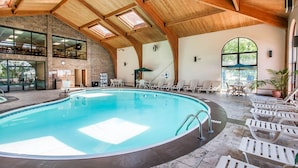 An indoor swimming pool with a wooden ceiling, lounge chairs, and a view of the outdoors. - Comfort Inn at Thousand Hills (Branson)